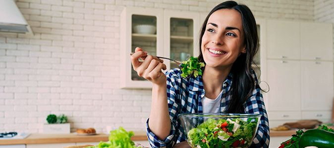 Imagem de uma mulher comendo salada