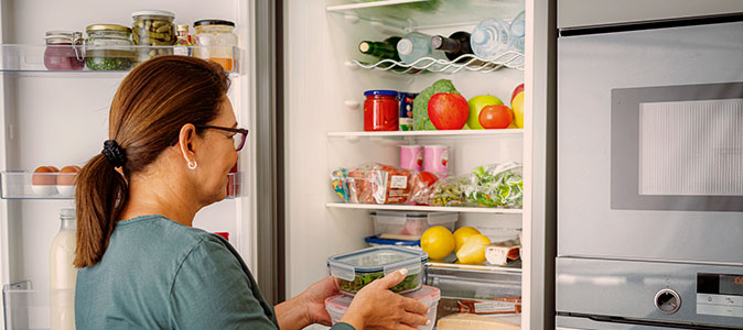 imagem de uma mulher guardando alimentos na geladeira