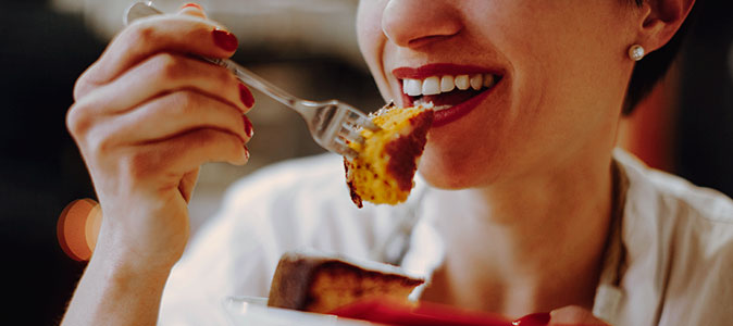 Imagem de uma mulher sorridente comendo bolo