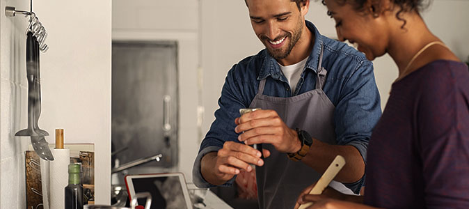 Casal cozinhando juntos e adicionando pimenta moída