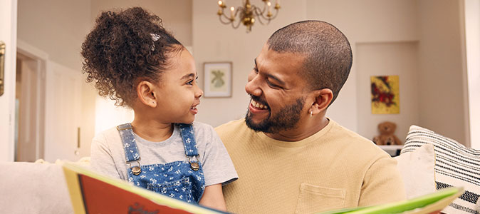 imagem de um pai sorrindo com sua filha no colo