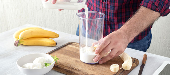 rapaz prepara vitamina com banana, queijo e leite