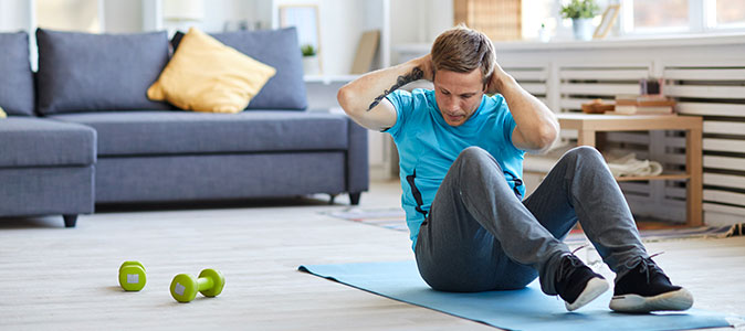 rapaz realiza exercícios na sala de casa