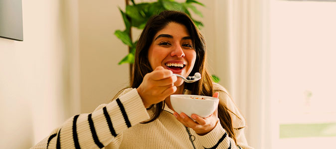 Imagem de uma mulher com um recipiente prestes a comer segurando uma colher