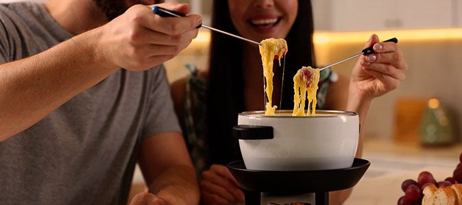 Imagem de um casal pegando prestes a comer fondue