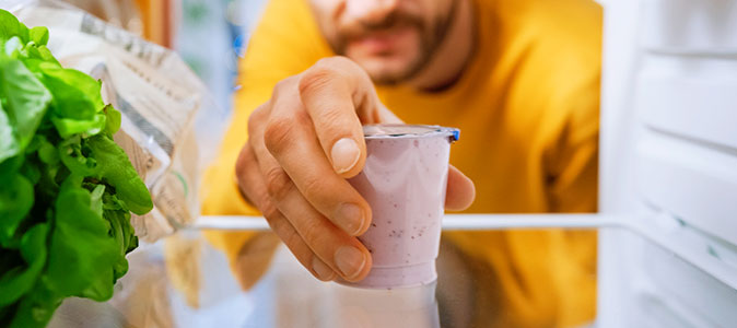 rapaz abre geladeira para pegar iogurte