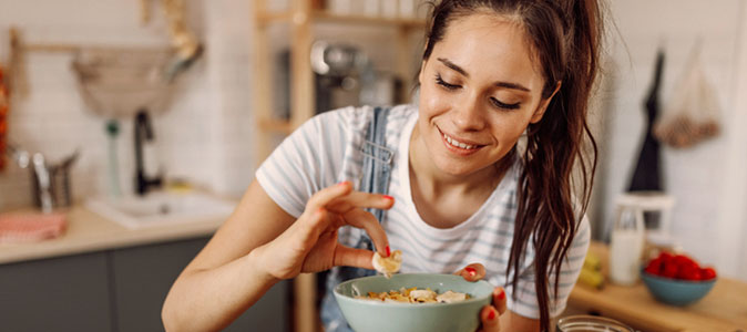 imagem de uma mulher pegando um alimento de um recipiente