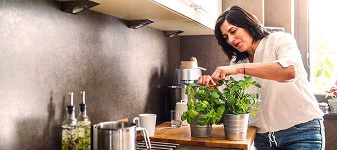 mulher em uma cozinha colhe temperos 