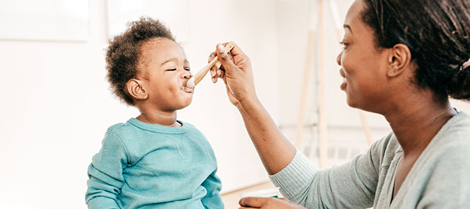 mãe dando iogurte para seu filho bebê